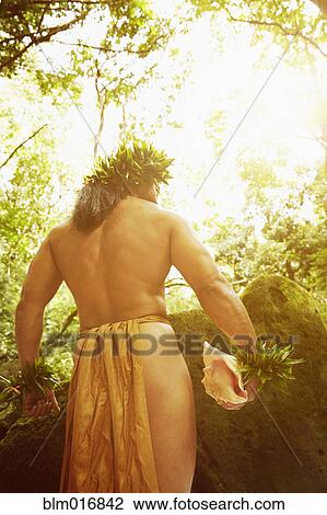 Stock Image - Hawaiian man in traditional outfit in jungle. Fotosearch