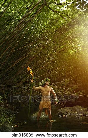 Stock Photography - Hawaiian man in traditional outfit holding torch. Fotosearch