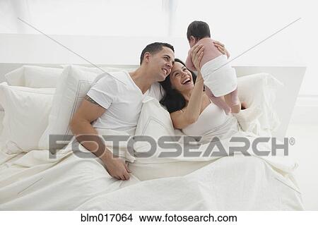 Picture - Hispanic family relaxing in bed. Fotosearch