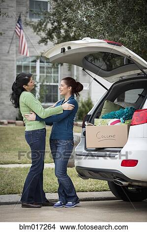 Picture - Hispanic mother helping daughter pack for college. Fotosearch