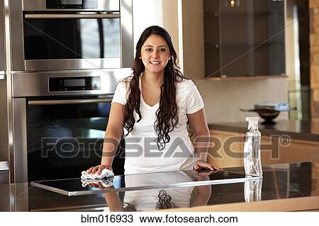 Stock Image - Hispanic woman cleaning kitchen. Fotosearch