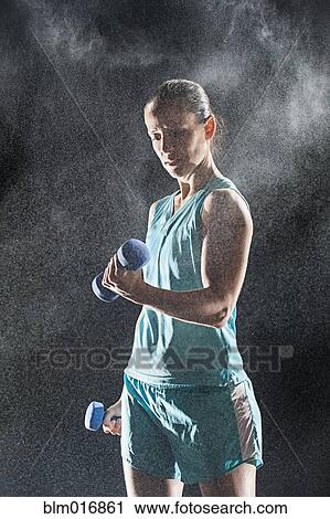 Stock Image - Hispanic woman lifting weights in rain. Fotosearch