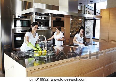 Stock Image - Hispanic women cleaning kitchen. Fotosearch