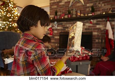 Picture - Mixed race boy opening Christmas present. Fotosearch