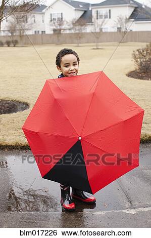 Stock Photograph - Mixed race boy playing with umbrella in rain. Fotosearch