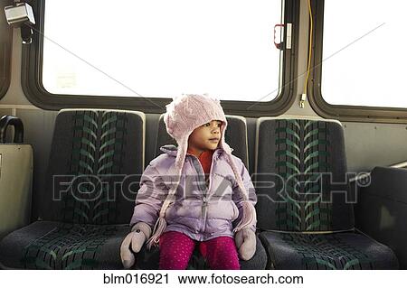 Stock Image - Mixed race girl in hat and gloves riding bus. Fotosearch