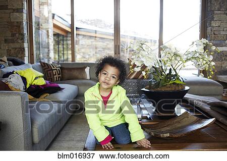 Mixed race girl sitting on coffee table View Large Photo Image Stock Photo - Mixed race girl sitting on coffee table. Fotosearch