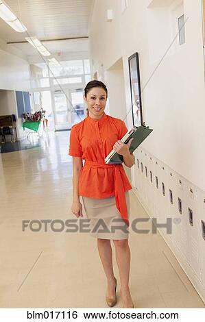 Mixed race teacher holding clipboard in school hallway View Large Photo Image Stock Photograph - Mixed race teacher holding clipboard in school hallway. Fotosearch