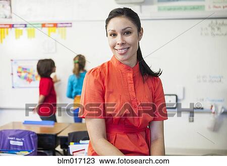 Stock Image - Mixed race teacher smiling in classroom. Fotosearch