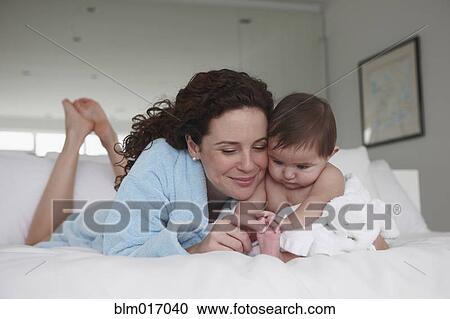 Mother and baby relaxing on bed View Large Photo Image Stock Image - Mother and baby relaxing on bed. Fotosearch