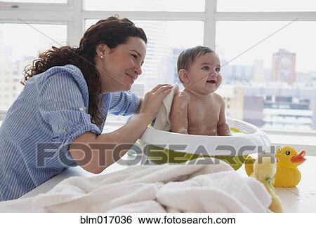 Stock Photograph - Mother bathing baby on counter top. Fotosearch