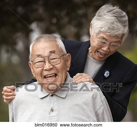 Stock Image - Older Asian couple laughing together outdoors. Fotosearch