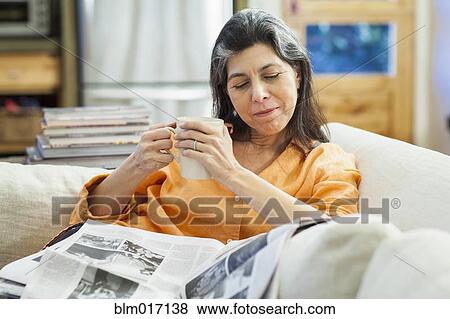 Older Hispanic woman reading newspaper on sofa View Large Photo Image Stock Photo - Older Hispanic woman reading newspaper on sofa. Fotosearch