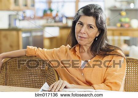 Older Hispanic woman reading newspaper at table View Large Photo Image Stock Photograph - Older Hispanic woman reading newspaper at table. Fotosearch