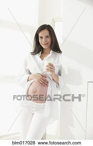 Stock Photo - Pregnant Hispanic woman holding her belly. Fotosearch