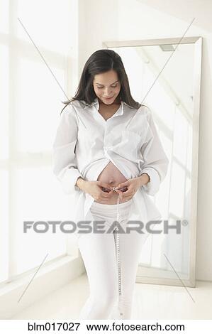 Pregnant Hispanic woman measuring her belly View Large Photo Image Stock Photo - Pregnant Hispanic woman measuring her belly. Fotosearch