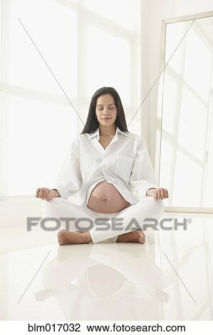 Stock Image - Pregnant Hispanic woman meditating. Fotosearch