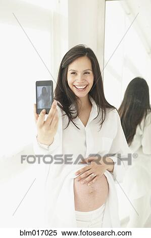 Stock Photography - Pregnant Hispanic woman taking picture of herself. Fotosearch