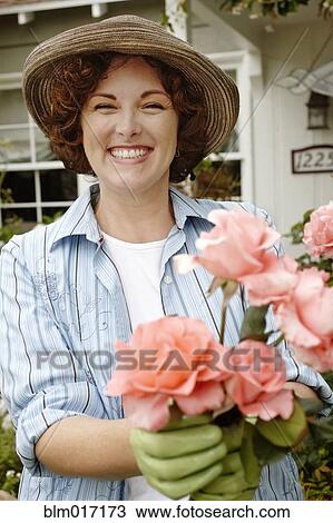 Stock Image - Smiling woman working in garden. Fotosearch