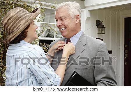 Woman adjusting husband's tie on front path View Large Photo Image Stock Photography - Woman adjusting husband's tie on front path. Fotosearch