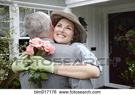 Stock Photograph - Woman hugging husband in garden. Fotosearch