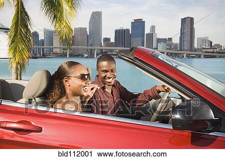 Stock Image - African American couple driving in convertible. Fotosearch