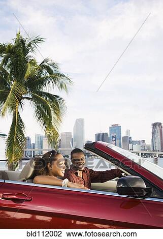 Stock Image - African American couple driving in convertible. Fotosearch