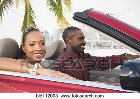 Stock Image - African American couple driving in convertible. Fotosearch