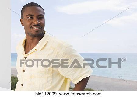Stock Photo - African American man standing on beach. Fotosearch