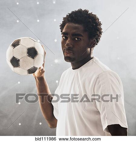 Stock Photograph - Black soccer player holding ball. Fotosearch