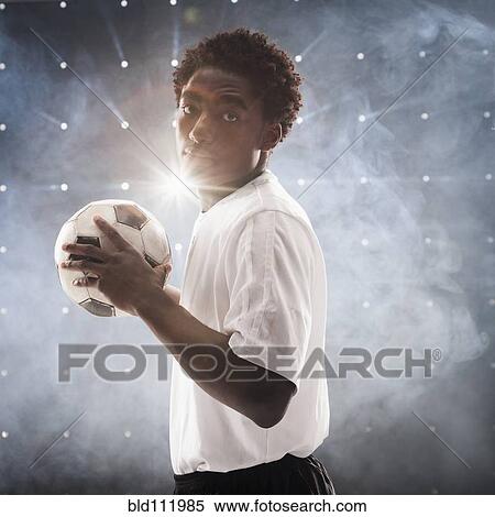 Stock Photography - Black soccer player holding ball. Fotosearch