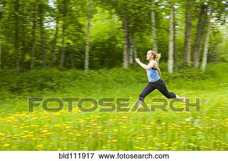 Stock Photo - Blurred view of Caucasian woman running in tall grass. Fotosearch
