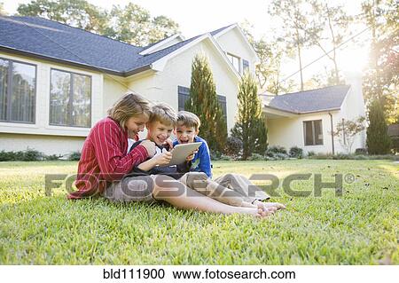 Caucasian boys using digital tablet on lawn View Large Photo Image Stock Image - Caucasian boys using digital tablet on lawn. Fotosearch