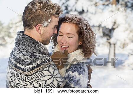 Stock Image - Caucasian couple hugging in snow. Fotosearch