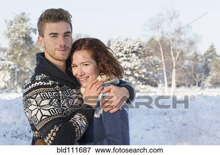 Stock Photo - Caucasian couple hugging in snow. Fotosearch
