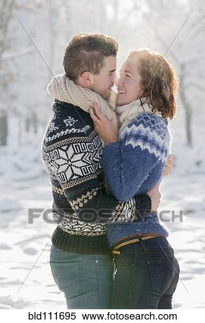 Stock Photography - Caucasian couple hugging in snow. Fotosearch