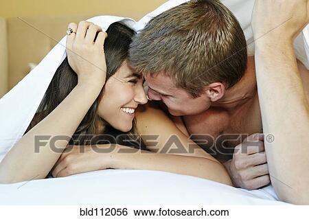 Stock Photograph - Caucasian couple kissing under sheet. Fotosearch