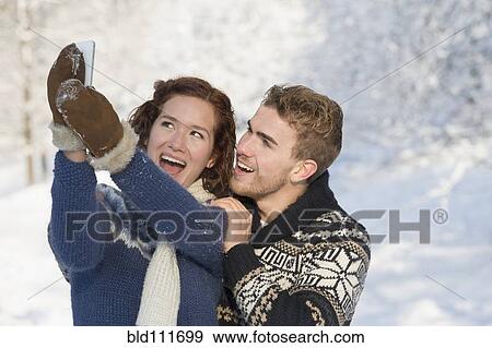 Caucasian couple taking pictures in snow View Large Photo Image Stock Photo - Caucasian couple taking pictures in snow. Fotosearch