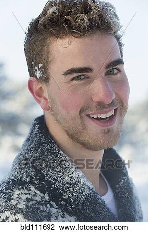 Stock Image - Caucasian man smiling in snow. Fotosearch