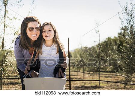 Stock Photo - Caucasian mother and daughter smiling in olive grove. Fotosearch