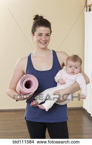 Picture - Caucasian mother holding baby in yoga studio. Fotosearch