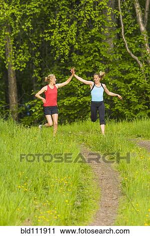 Caucasian runners high fiving on path View Large Photo Image Stock Image - Caucasian runners high fiving on path. Fotosearch