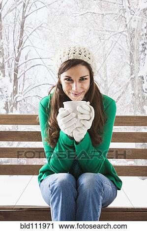 Stock Image - Caucasian woman having cup of coffee in snow. Fotosearch