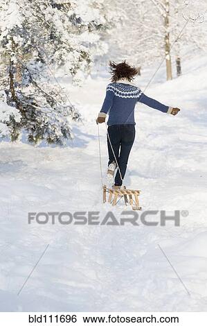Stock Photograph - Caucasian woman pulling sled in snow. Fotosearch