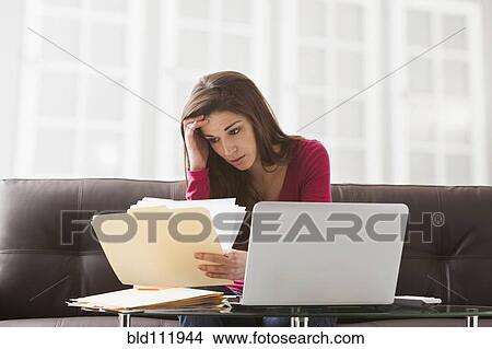 Caucasian woman reading papers at laptop View Large Photo Image Picture - Caucasian woman reading papers at laptop. Fotosearch