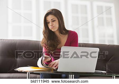 Caucasian woman reading papers at laptop View Large Photo Image Stock Photography - Caucasian woman reading papers at laptop. Fotosearch