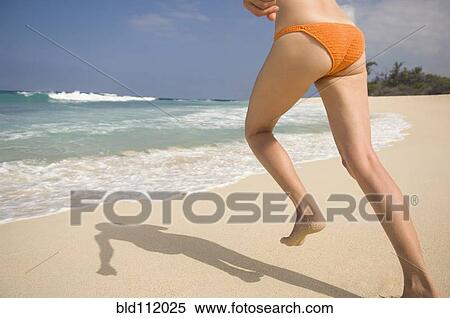 Stock Photography - Caucasian woman running in bikini on beach. Fotosearch