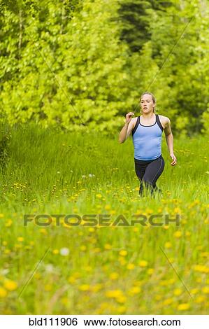 Stock Photograph - Caucasian woman running in tall grass. Fotosearch