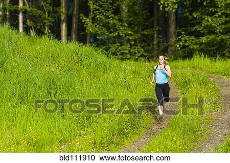Stock Image - Caucasian woman running on path. Fotosearch