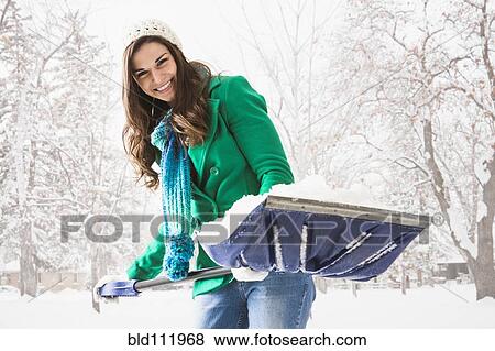 Stock Photo - Caucasian woman shoveling snow outdoors. Fotosearch